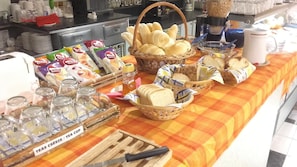 A buffet table with various food items and beverages, including bread, pastries, and tea.
