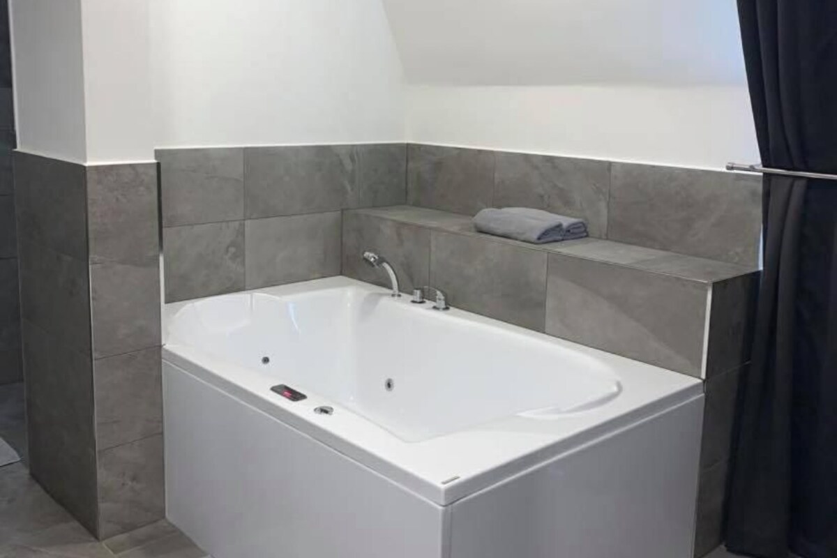 A modern bathroom with a freestanding bathtub, a towel rack, and a shower area.