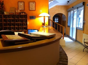 A reception desk with a lamp, a computer, and a sign indicating a taxi service.