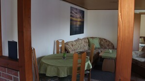 A cozy room with a dining table, chairs, a sofa, and a painting on the wall.
