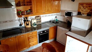 A compact kitchen with wooden cabinets, a granite countertop, a sink, a dishwasher, and a refrigerator. - Tropical finca, sea view, mountain panorama, sandy beach 5 minutes (Arico)
