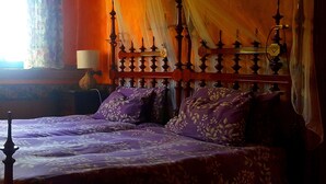 A bed with a wooden headboard, purple bedding, and draped curtains. - Tropical finca, sea view, mountain panorama, sandy beach 5 minutes (Arico)