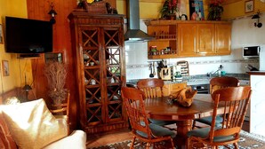 A cozy living room with a TV, wooden furniture, and a dining area with a table and chairs. - Tropical finca, sea view, mountain panorama, sandy beach 5 minutes (Arico)