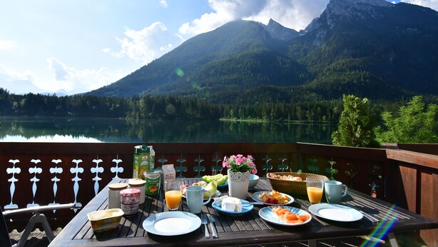 Una mesa dispuesta con alimentos para el desayuno y una vista panorámica de la montaña.