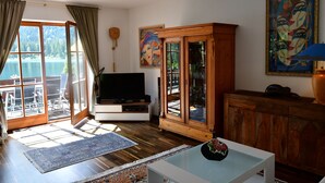Una sala de estar con televisor, aparador de madera y un cuadro.