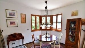 Un comedor con una mesa redonda, sillas, una alfombra y un aparador de madera con libros.