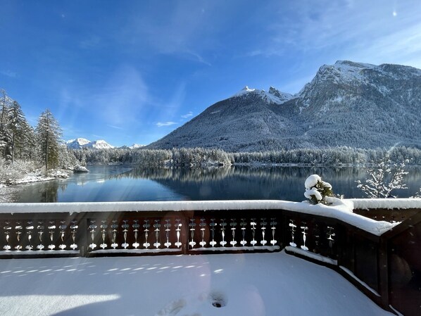 A snow-covered mountain landscape with a lake and a wooden fence in the foreground.