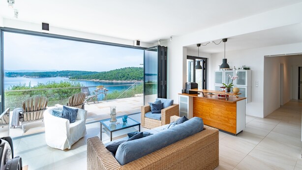 Un amplio espacio de sala con un gran ventanal que da a un balcón con vistas a un paisaje pintoresco.