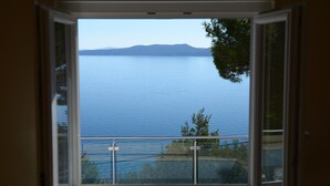 A view through a window of a calm lake with distant mountains, a clear sky, and some greenery. - Private oasis for up to 6 adults with swimming pool, sea view & 2 beaches nearby (Marušići)