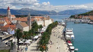 A coastal city with a marina, palm-lined promenade, historic buildings, and mountains in the background. - Private oasis for up to 6 adults with swimming pool, sea view & 2 beaches nearby (Marušići)