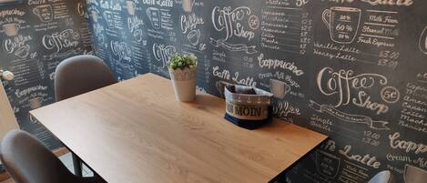 Una mesa de madera con una planta en maceta y un asidero para taza, junto con un cartel.