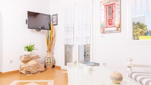Een moderne woonkamer met een flatscreentelevisie, een decoratieve vaas, een potplant en uitzicht buiten door een raam.