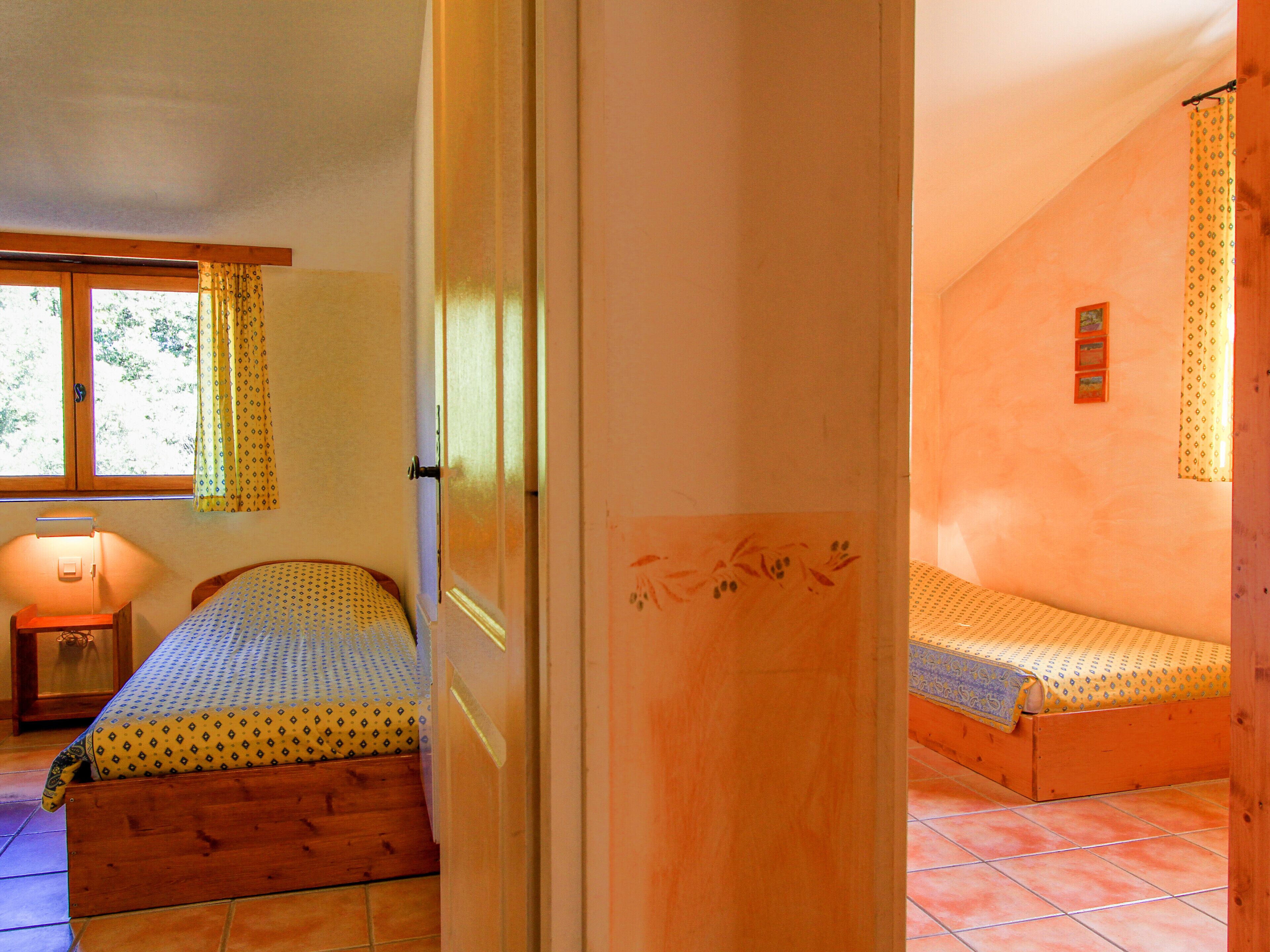 Ein Schlafzimmer mit einem Bett, einem Nachttisch, einem Fenster mit Vorhängen und einem Bild an der Wand.