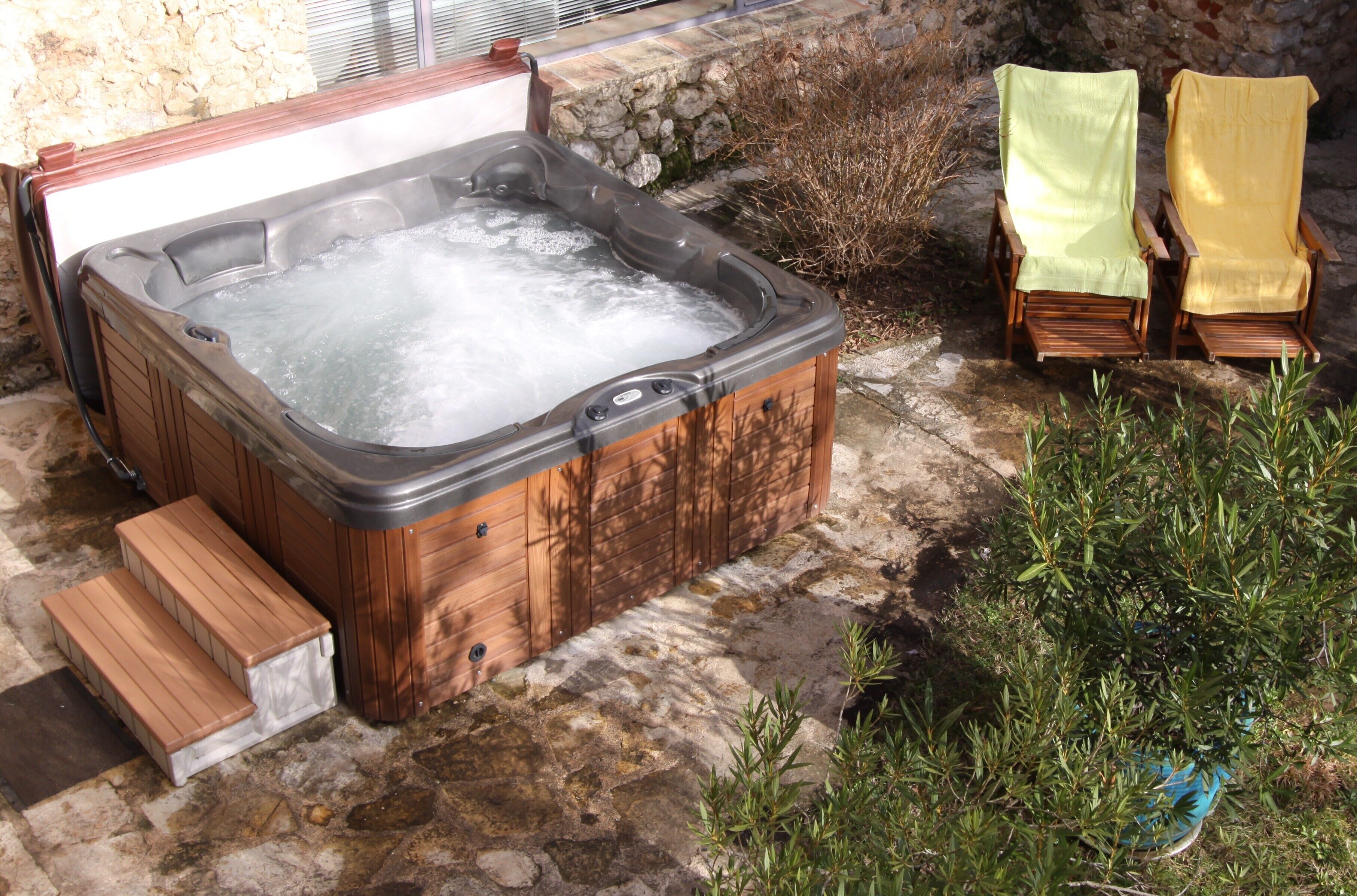 Un jacuzzi con escalones de madera y una pared de piedra al fondo.
