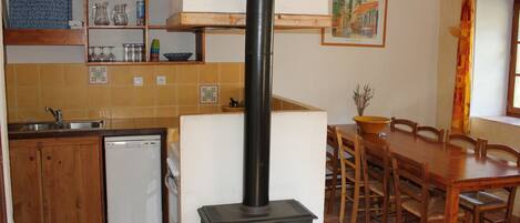 A kitchen with a wood stove, a dishwasher, and a dining area with a table and chairs.