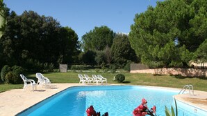 A swimming pool with white chairs and a ladder, surrounded by greenery and trees. - La Farigoule for 6 persons rental with shared pool nature and calm (Flayosc)