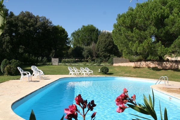 A swimming pool with white chairs and a ladder, surrounded by greenery and trees. - La Farigoule for 6 persons rental with shared pool nature and calm (Flayosc)
