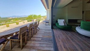 A wooden deck with outdoor furniture, a green sofa, and a view of the countryside. - ALZONE_6-bedroom villa with a swimming pool and sea views in a quiet location (Porticcio)