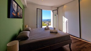 A modern bedroom with a large bed, a view of the outdoors, and a painting on the wall. - ALZONE_6-bedroom villa with a swimming pool and sea views in a quiet location (Porticcio)