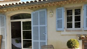 A patio area with a wooden table and chairs, a folding chair, and a potted plant. - Bastide du Soleil - Studio 2-4 people with private garden (Cannes)