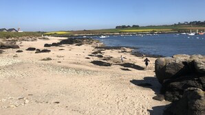 Ein Küstenstrand mit felsigem Gelände und Booten im Wasser.