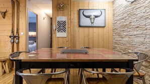 A wooden-paneled room with a large dining table, chairs, a clock, and a bull skull artwork. - COZY APARTMENT RENOVATED CITY CENTER AVENUE LECLERC WIFI AND PRIVATE COVERED PARKING (CAUTERETTS)