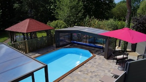 Ein Garten mit Swimmingpool, Laube und Gartenmöbeln.