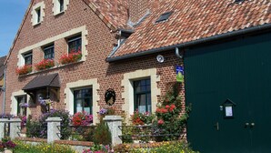 Ein zweistöckiges Backsteingebäude mit einem Ziegeldach, einer grünen Garagentür und einem Blumenbeet im Vorgarten.