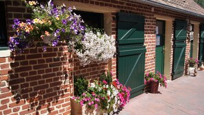 Ein Backsteinhaus mit hängenden Blumenkörben und grünen Türen.