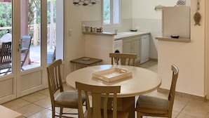 Cocina compacta con comedor, vigas de madera, ventana y vista al exterior.