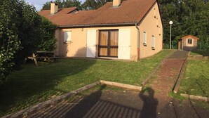 Una casa de un solo piso con techo de tejas, una puerta principal y un pequeño jardín.