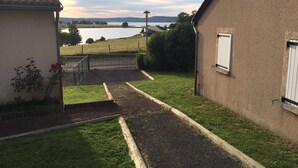 Un sendero que lleva a una casa con vista a un lago y colinas al fondo.