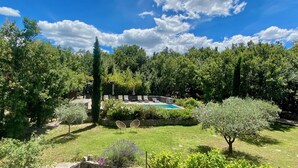 Un jardín con piscina, muros de piedra y diversas plantas.