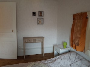 A bedroom with a wooden desk, a bedside table with a lamp, and a bed with a patterned bedspread. - Ideal spa / Holiday / Weekend (Mont-Dore)