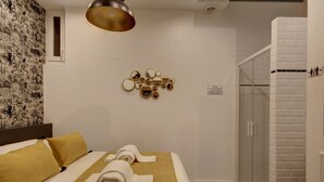 A hotel room with a bed, a shower, and a wall-mounted mirror art piece.