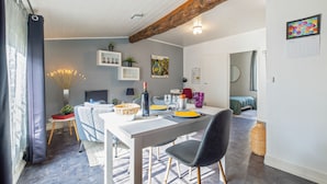 Un espace repas avec une table blanche, des chaises noires et une poutre en bois au plafond.