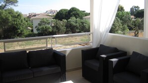 A balcony with wicker furniture and a view of a town.