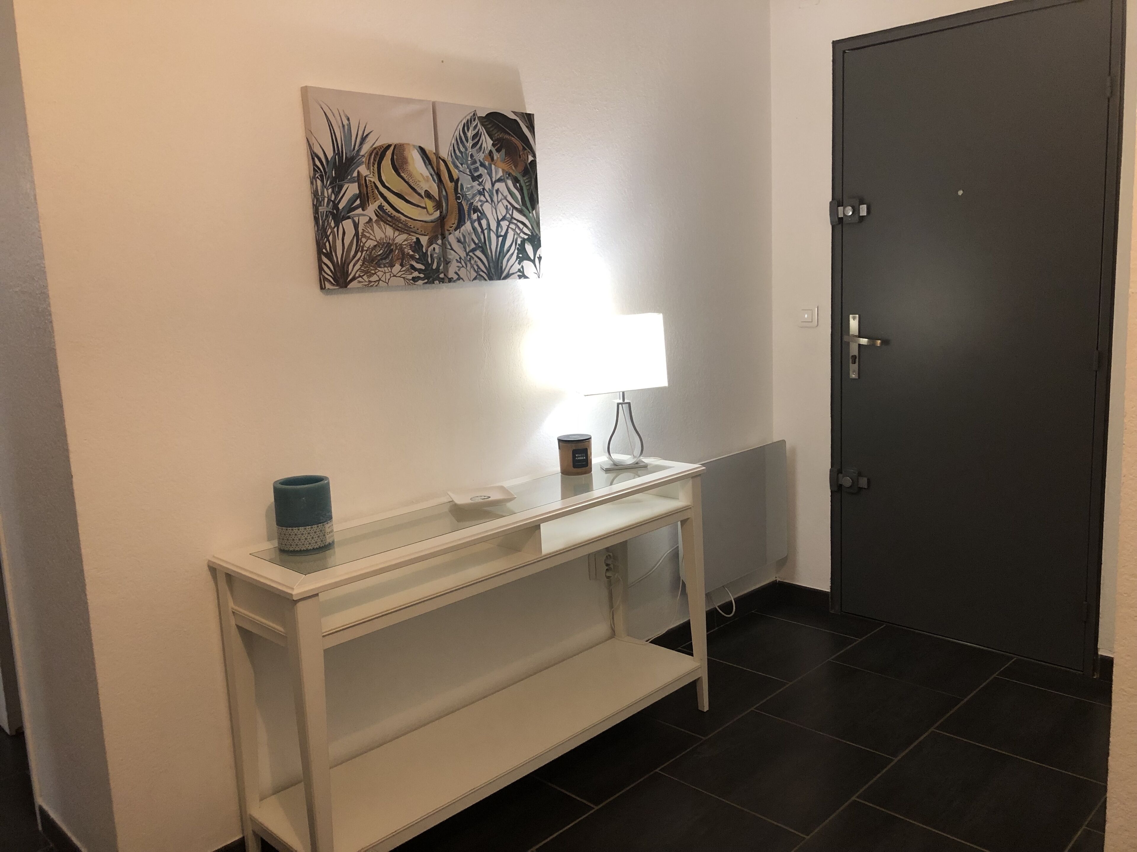 A hallway with a white console table, a lamp, and a door.
