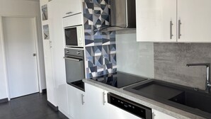 A modern kitchen with white cabinets, a built-in oven, a microwave, a dishwasher, and a stainless steel range hood. - Canet Sud Very nice apartment of 85 m² 150 m from the beach Parking Air conditioning Wi-Fi (Canet-En-Roussillon)