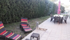 Un espacio al aire libre con un patio, dos sillones de descanso, una mesita y una mesa de comedor con sillas.