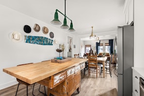 Une cuisine avec un îlot central en bois, un coin repas avec des chaises et un réfrigérateur.