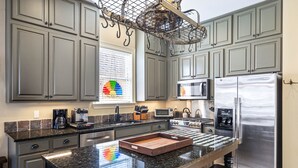 Una cocina con armarios grises, un refrigerador de acero inoxidable, un microondas y una cafetera.
