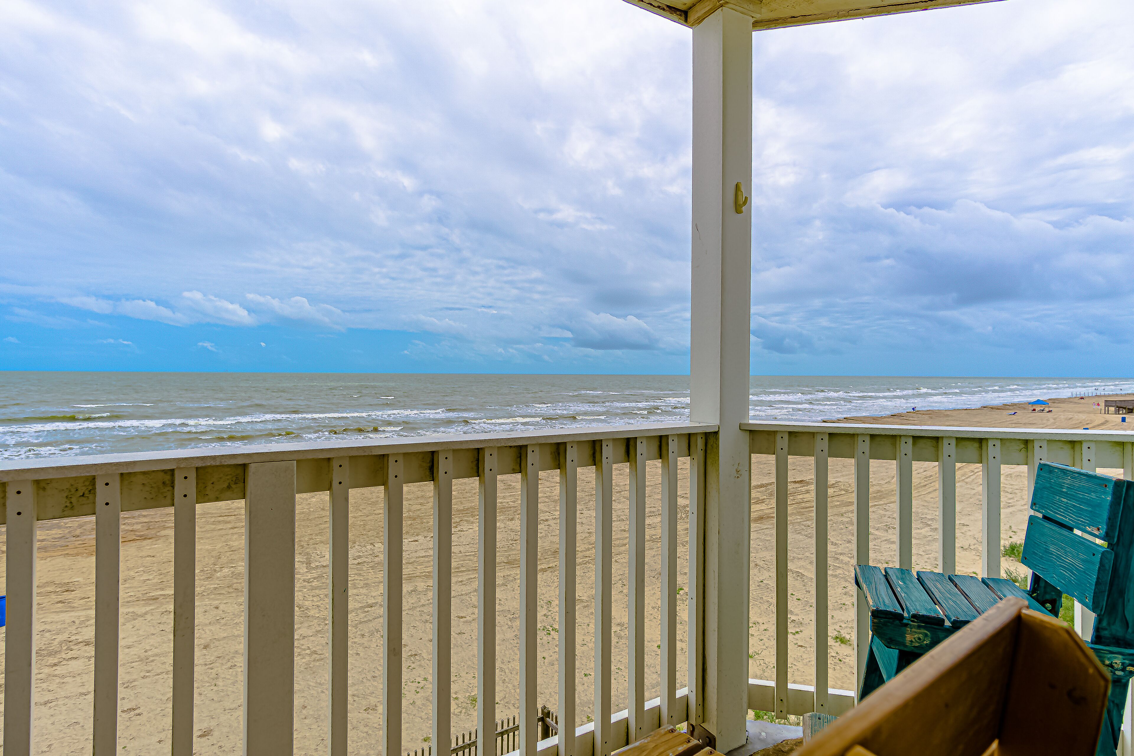 Vista a la playa desde un porche cubierto con un banco de madera.