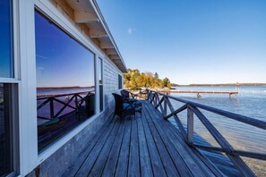 Eine Holzterrasse mit Blick auf das Wasser und einem Dock in der Ferne.
