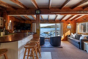 Ein gemütliches Blockhaus-Interieur mit einer Holztheke, einer Sitzecke und Blick auf einen See.