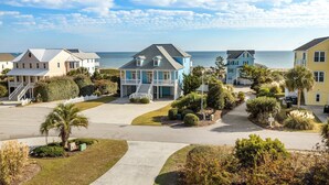 A coastal residential area with houses, a clear sky, and a view of the ocean. - Dreamsicle: Pool, Pup & Family Fun (Emerald Isle)