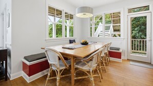 Un comedor con una mesa de madera, sillas de mimbre y una lámpara colgante.