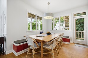 A dining area with a wooden table, wicker chairs, and a pendant light.