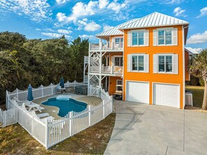 A two-story house with a swimming pool, white picket fence, and a garage.