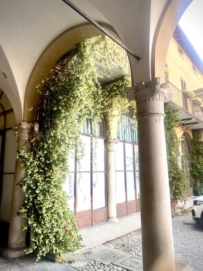 Un bâtiment doté d’arcades et de colonnes, recouvert de verdure.